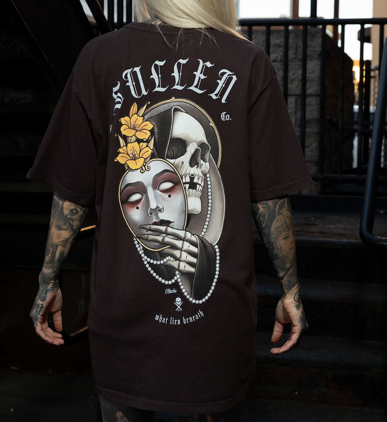 Person wearing a black t-shirt with a skull and floral design, standing outdoors.