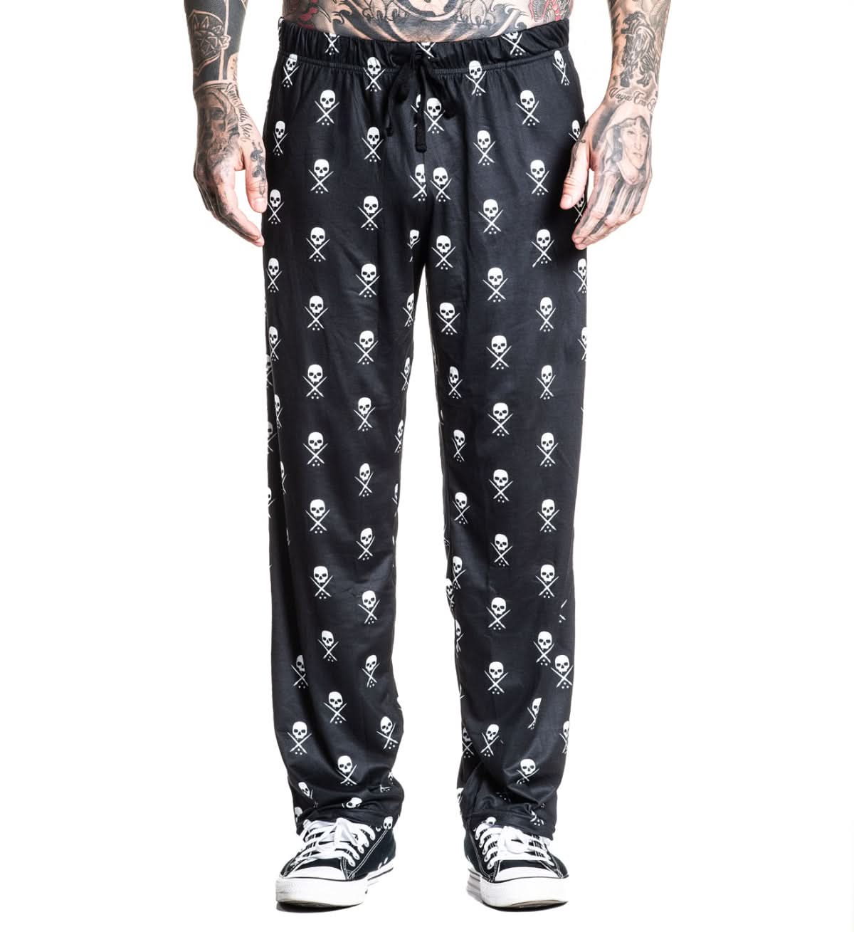 Black pants with skull and crossbones pattern worn by a person on a white background