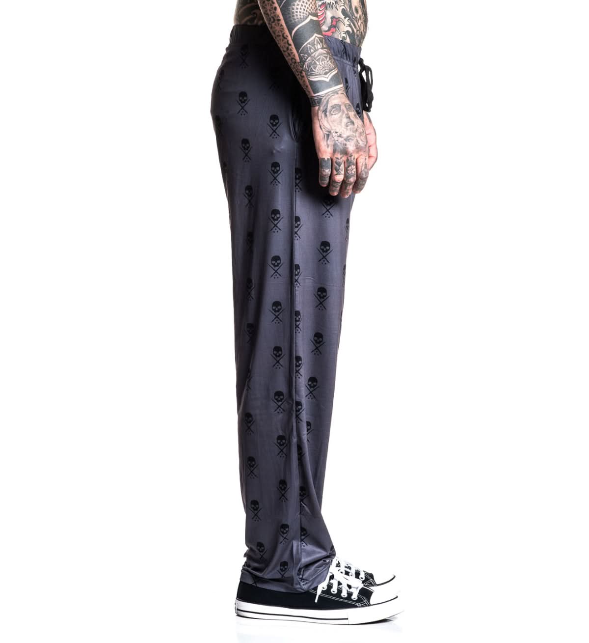 Person wearing black pants with skull pattern on a white background
