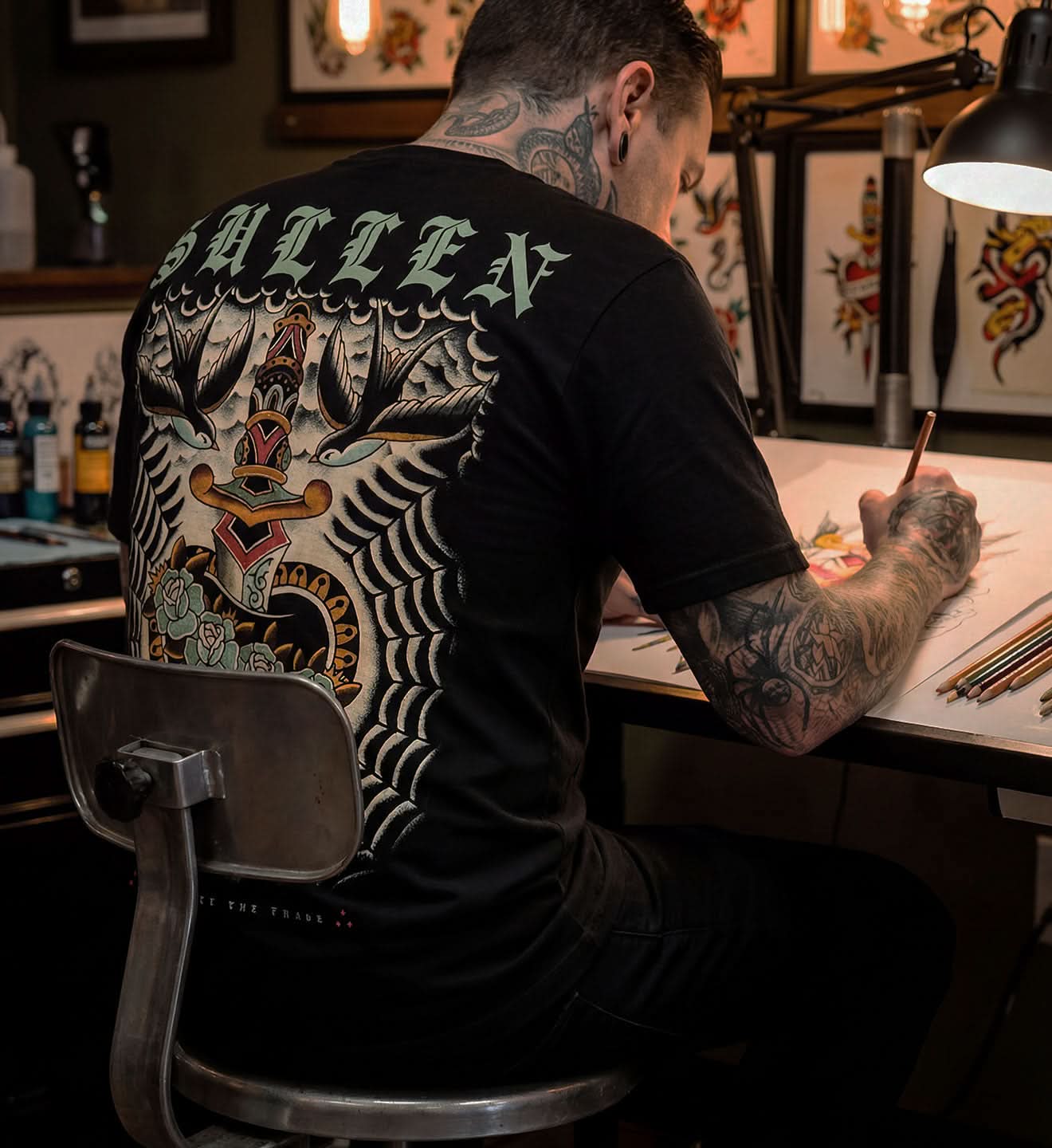 tattoo artist drawing with black sullen american traditional t shirt on