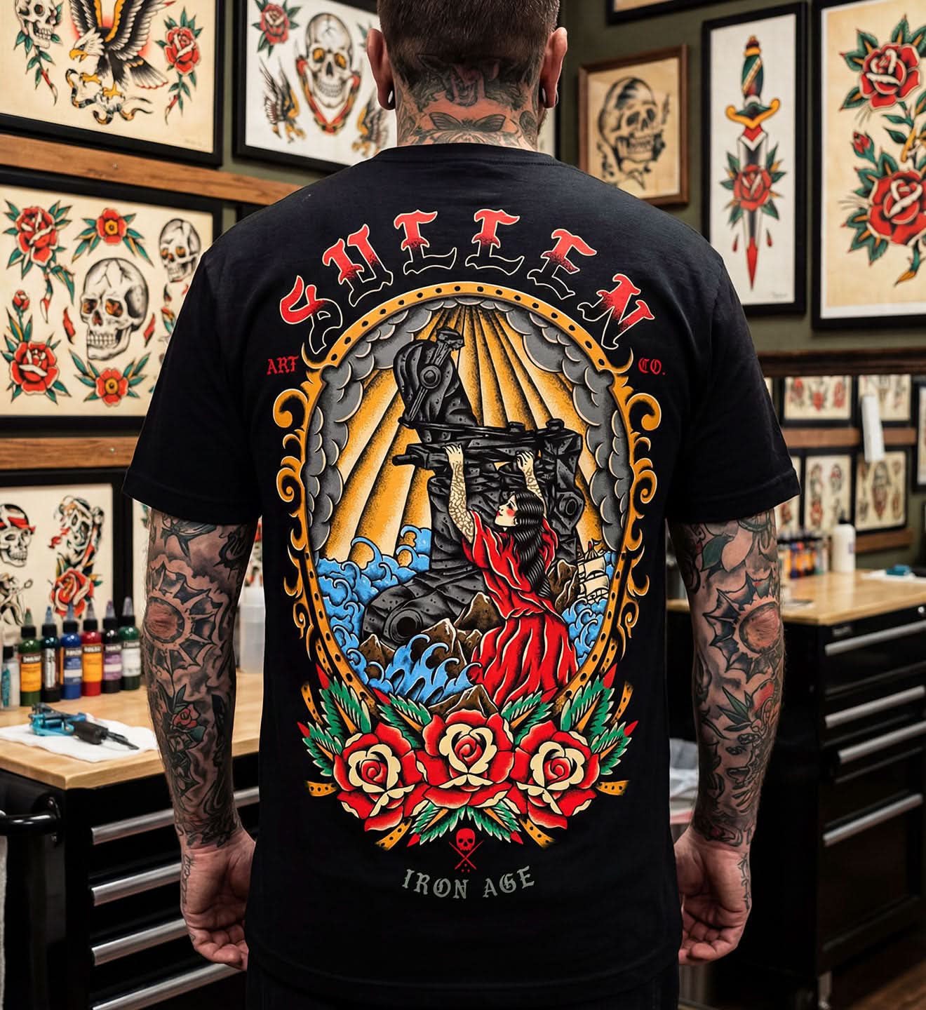Person wearing a black t-shirt with a colorful tattoo design on the back in a tattoo studio.