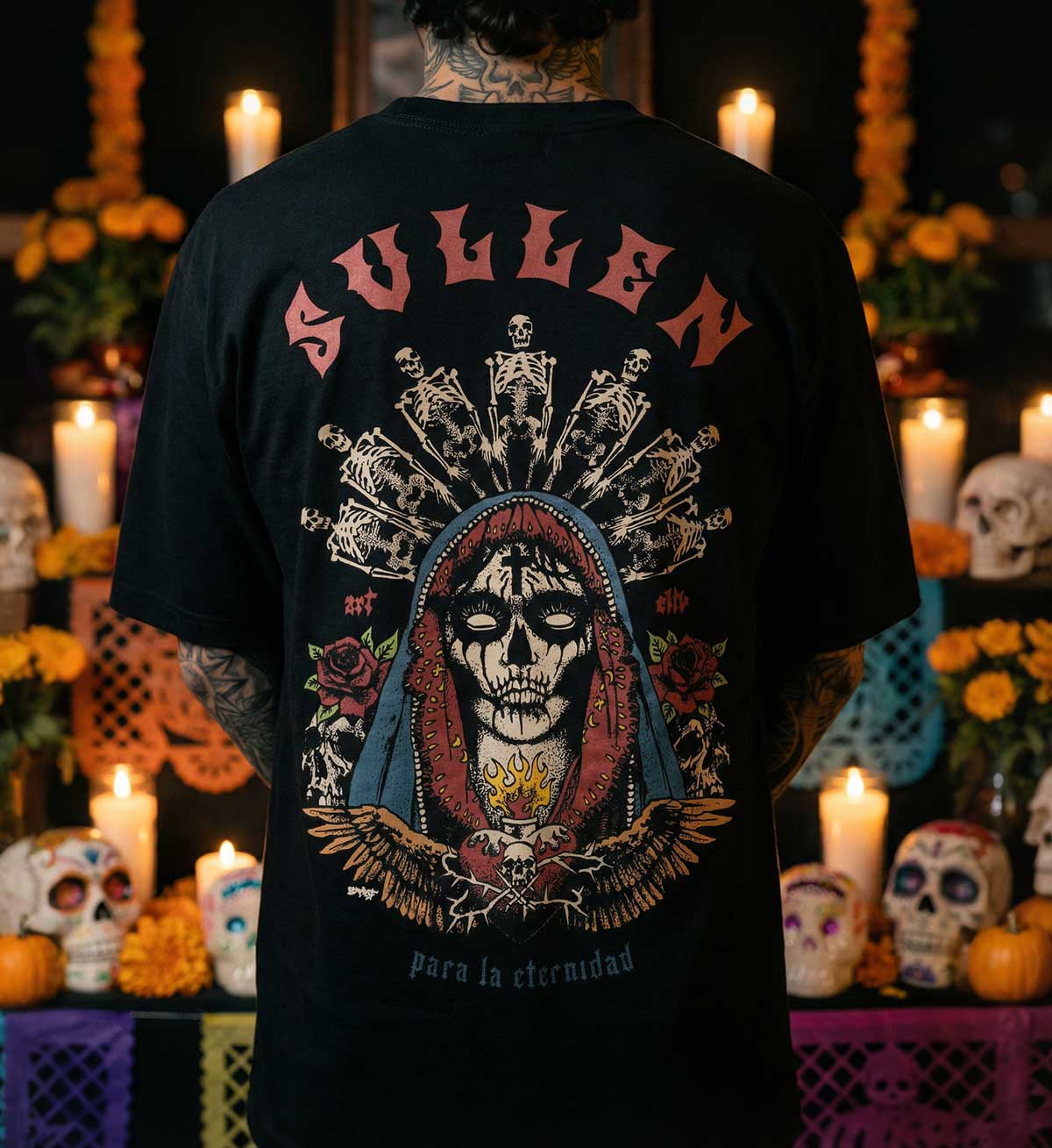 Person wearing a black t-shirt with a colorful skull design and 'Sullen' branding, set against a festive background with candles and decorations.