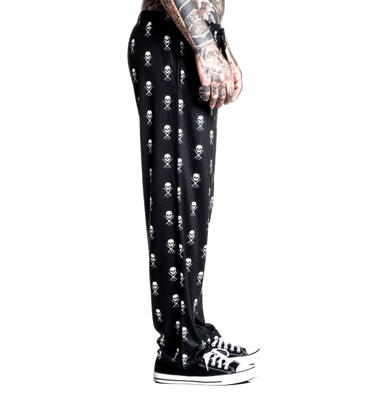 Black pants with skull and crossbones pattern worn by a person on a white background