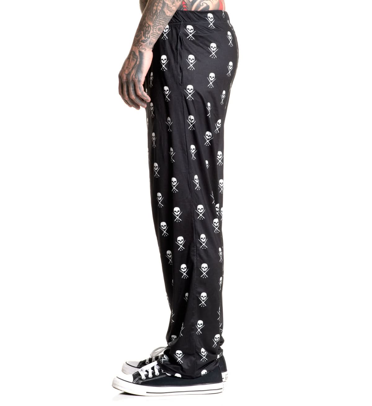 Black pants with skull and crossbones pattern worn by a person on a white background