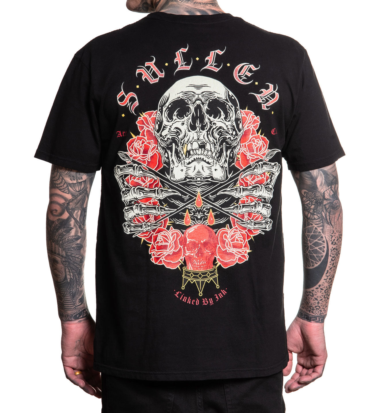 Black t-shirt with a skull and roses design on the back, worn by a person with tattoos.