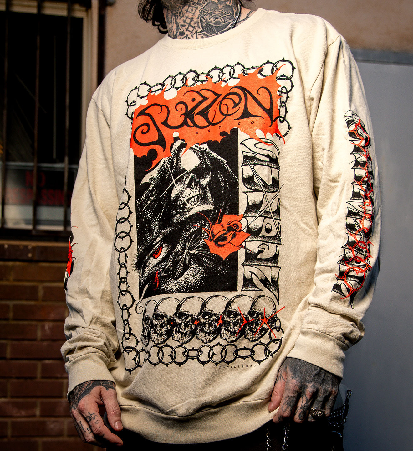 Person wearing a white long-sleeve shirt with intricate black, red, and orange graphic design.