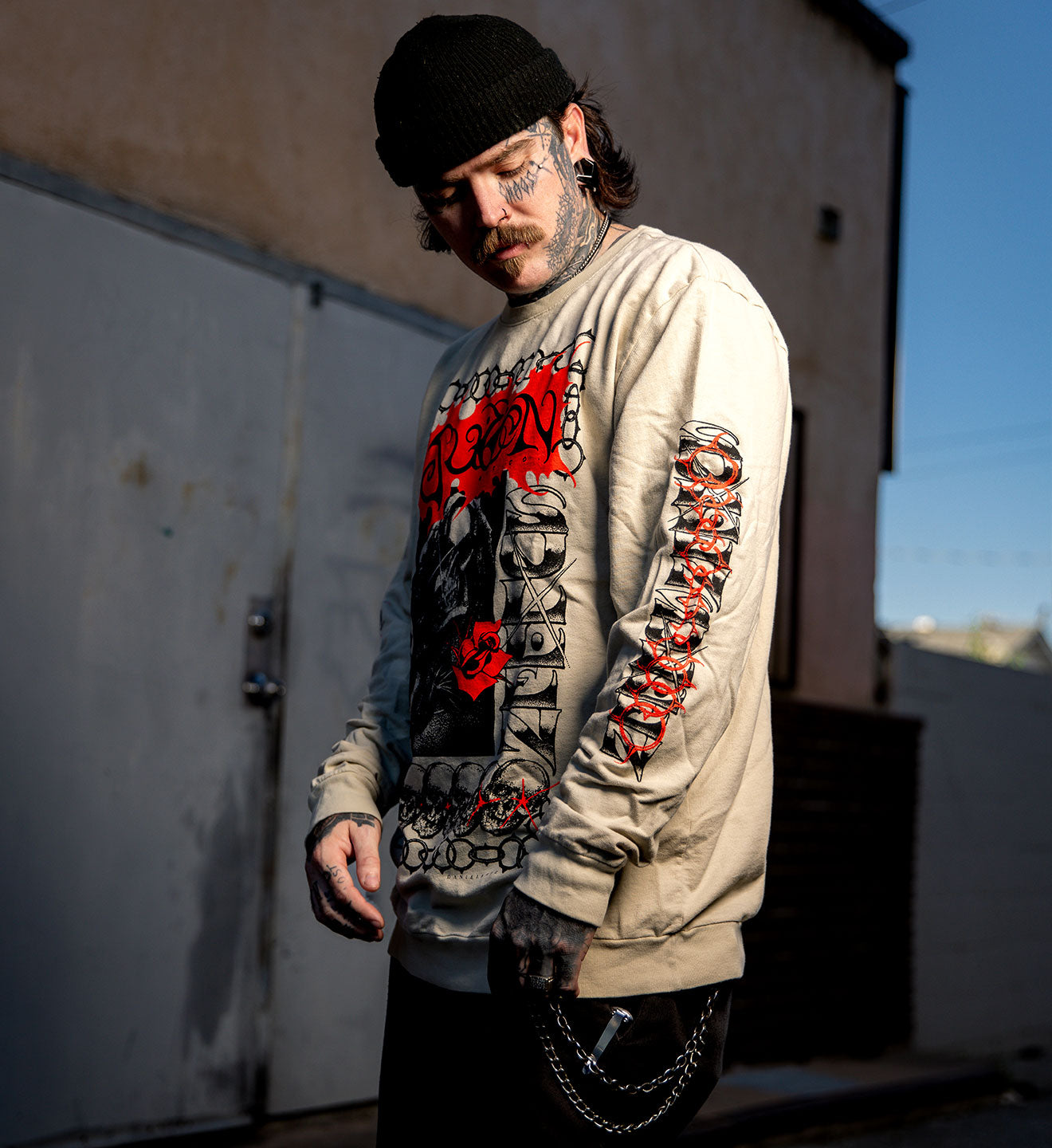 Man wearing a graphic long-sleeve shirt with tattoos outdoors