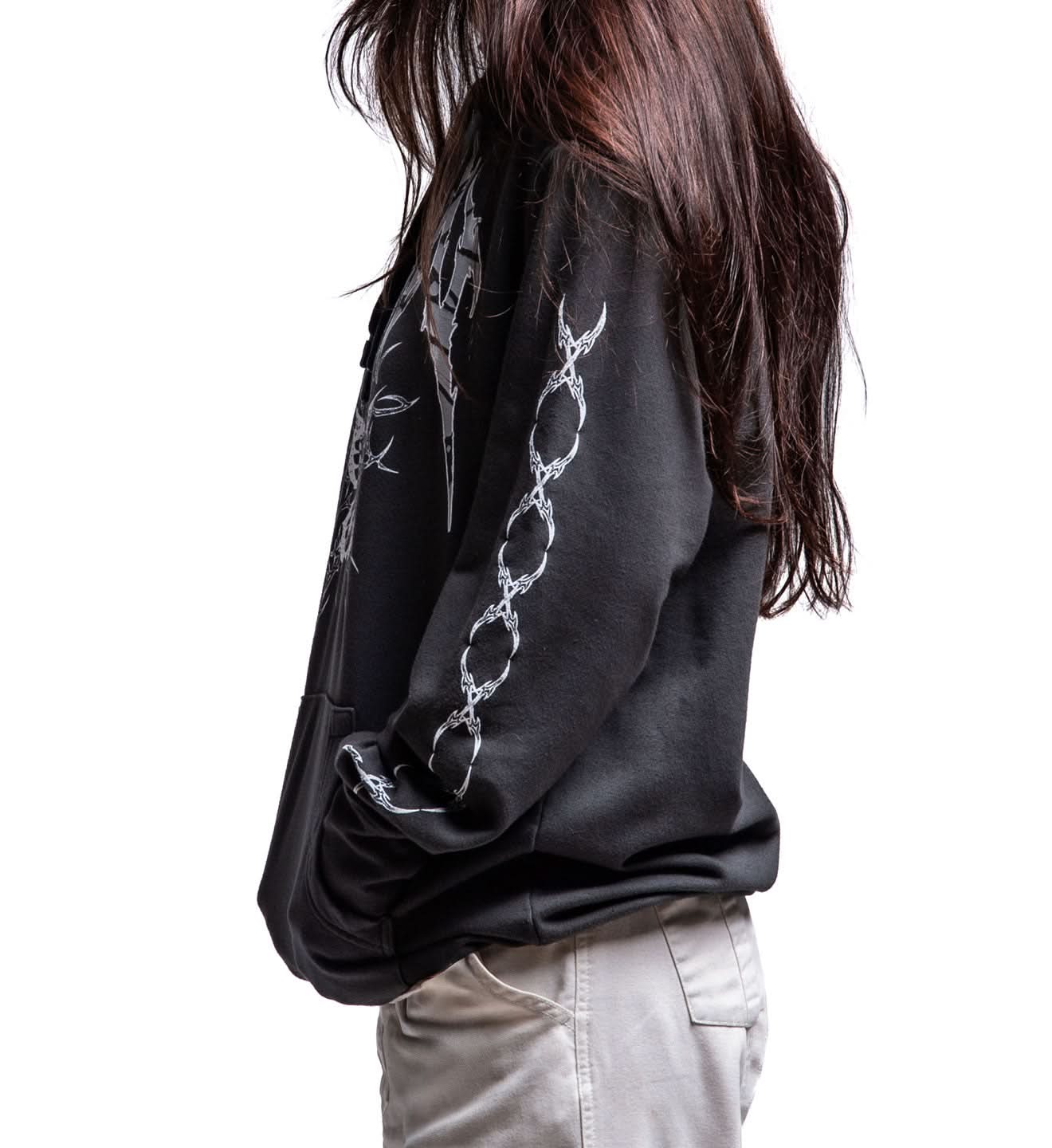 Person wearing a black long-sleeve shirt with white chain design on a plain background