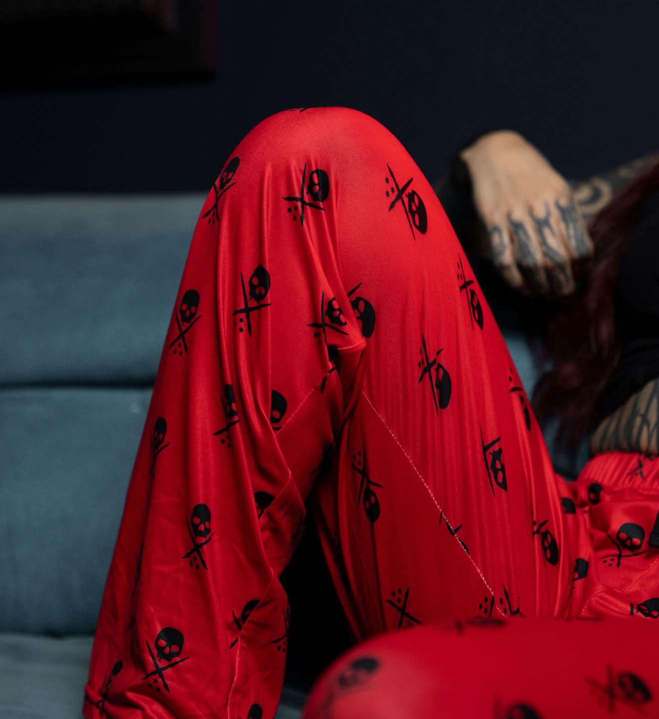 Person wearing a red outfit with black patterns sitting on a couch.