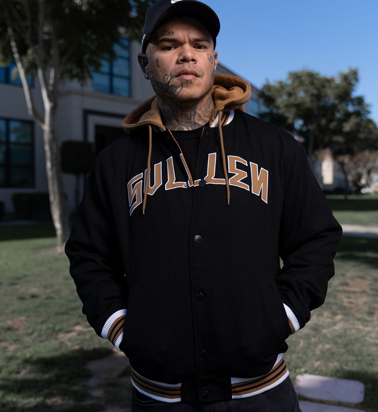 Person wearing a black letterman jacket with 'Gulliver' text, standing outdoors.