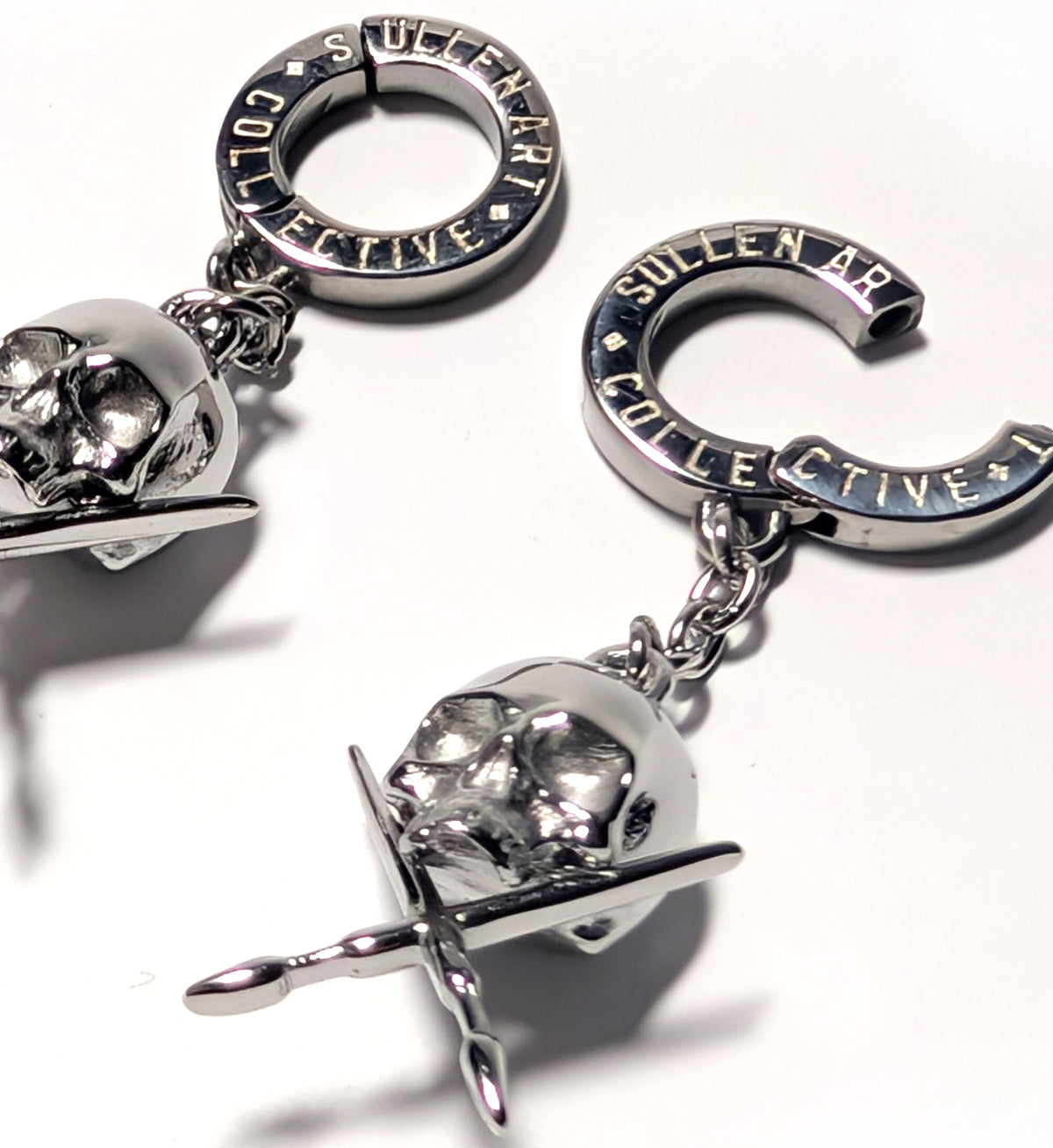Silver jewelry with 'Sullen Collective' branding on a white background