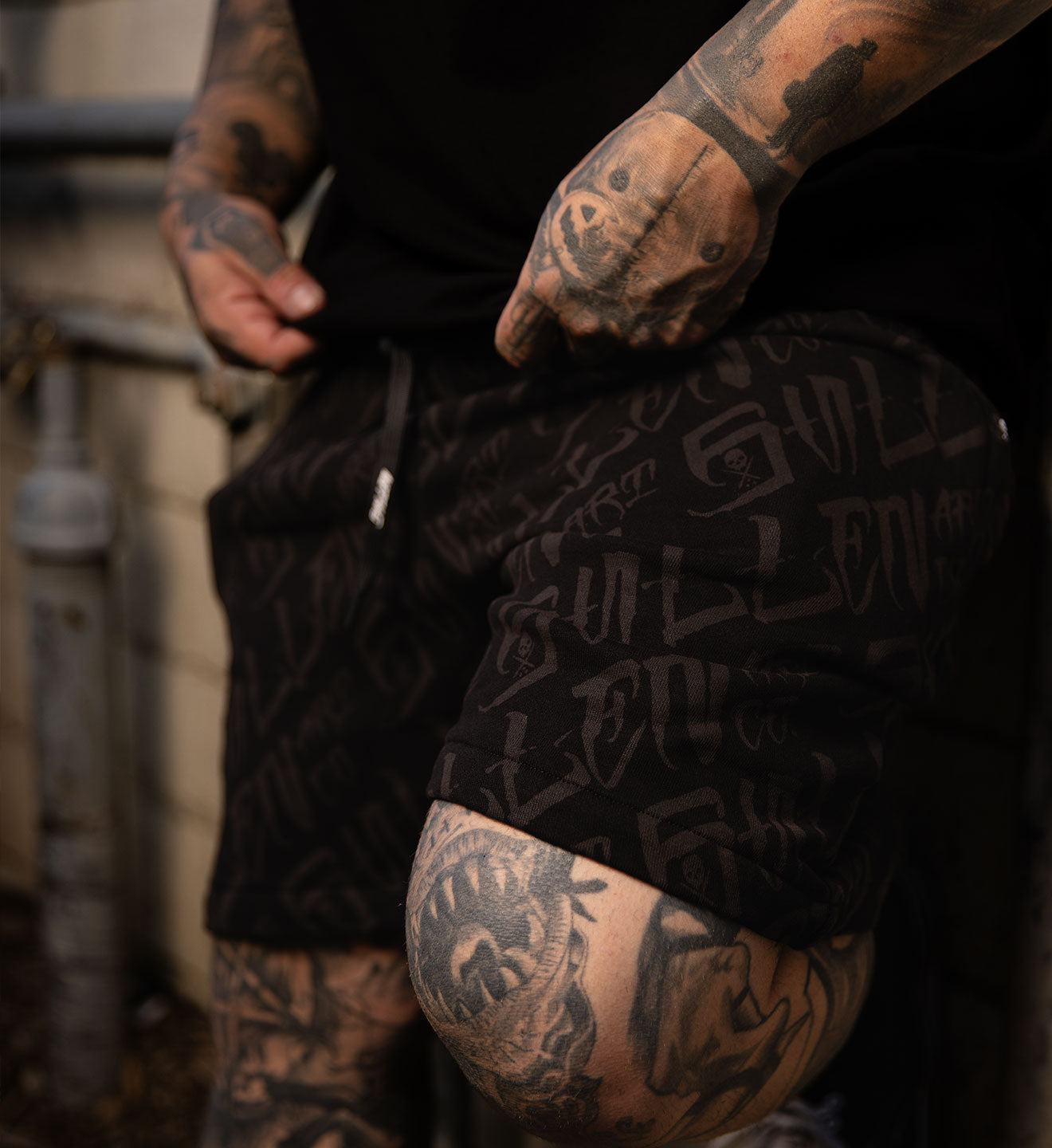 Person wearing a black jacket with visible tattoos on arms and legs.