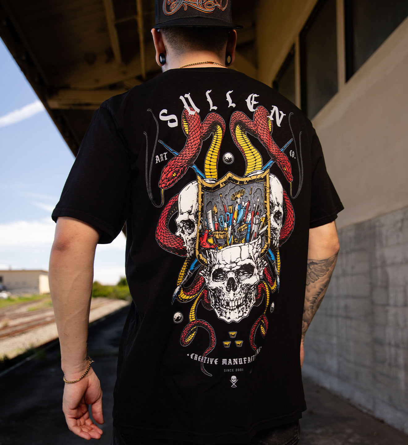 Person wearing a black 'Sullen' t-shirt with a graphic design on the back.