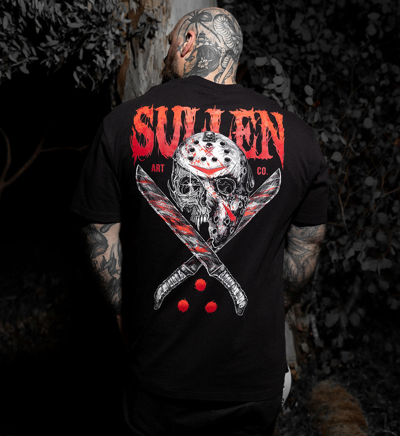 Person wearing a black t-shirt with a graphic design and 'Sullen' branding.