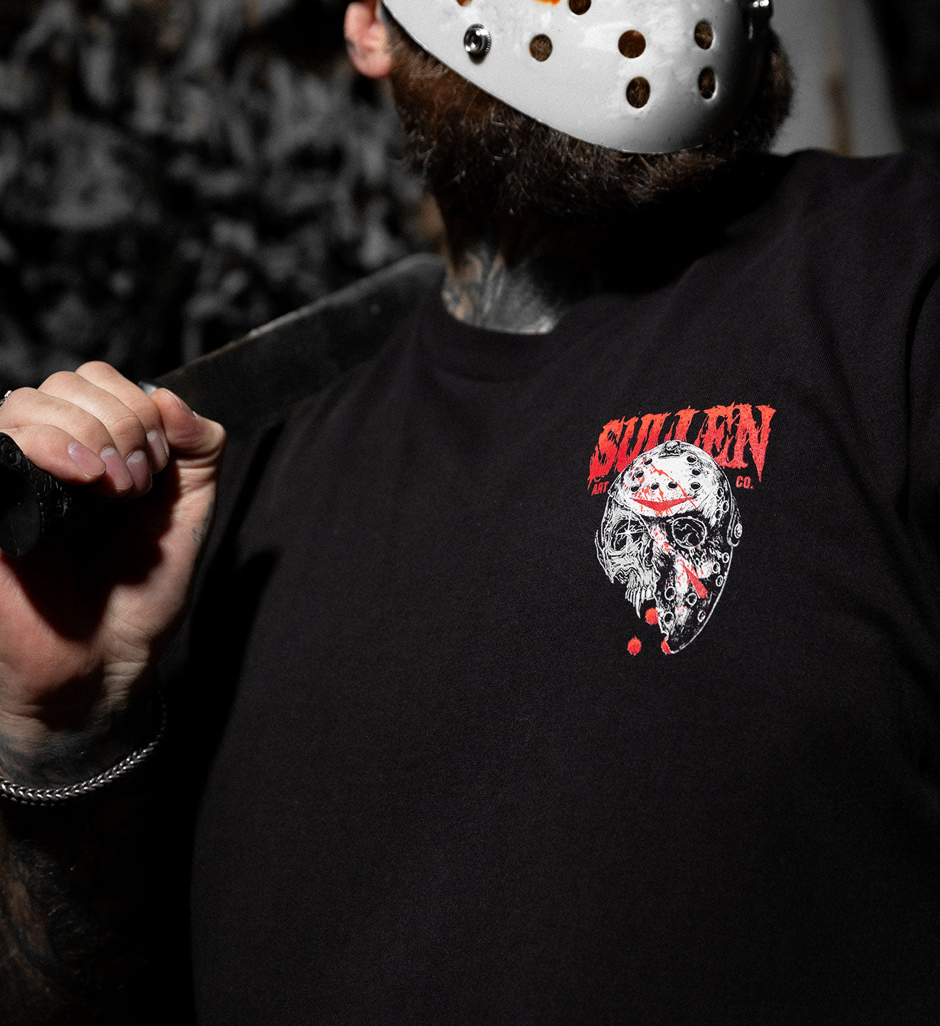 Person wearing a black t-shirt with a skull design and text, holding a knife.